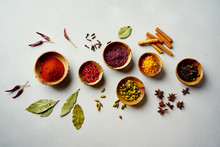 Various Colorful Spices In Wooden Bowls On Concrete Background. Top View. Different Types Of Pepper, Turmeric, Paprika, Rosemary, Chili, Cardamom, Cinnamon, Anise, Cloves.