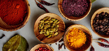Various Colorful Spices In Wood Bowls On Concrete Background. Top View With Copy Space. Different Pepper, Turmeric, Paprika, Rosemary, Chilly, Cardamom, Cinnamon, Anise, Cloves.
