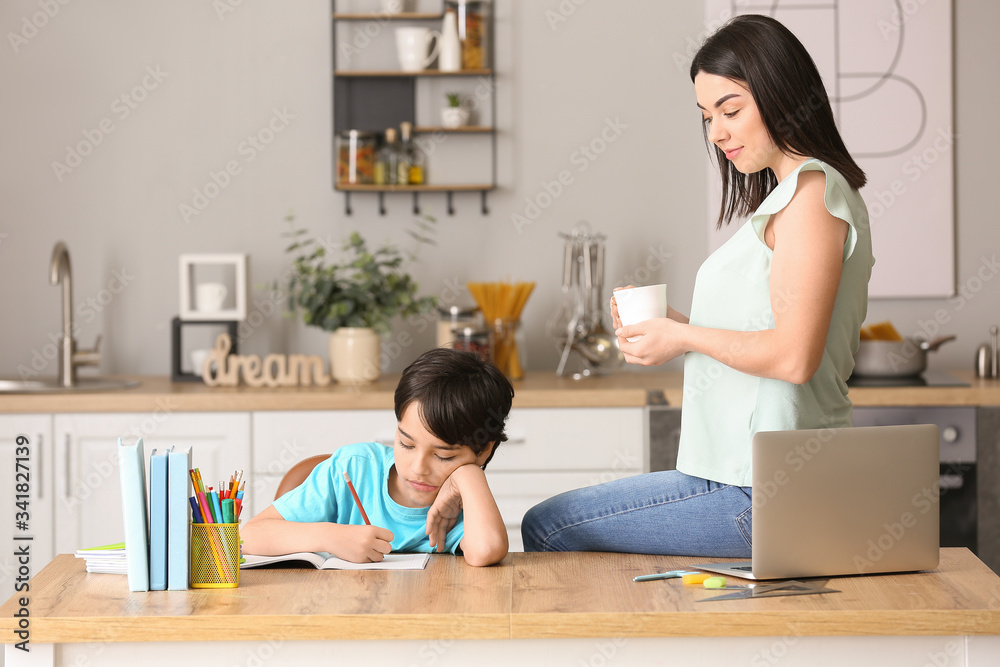 Little boy with his mother doing homework in kitchen