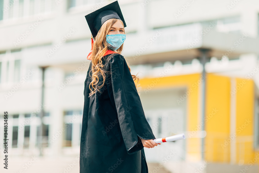 A graduate student in a medical mask, in a black graduation dress, with a  diploma in her hands. Graduation ceremony concept, quarantine, coronavirus  Stock Photo | Adobe Stock
