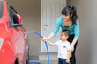 © ake1150 - Asian mother and her son having happy in home washing owner red car using hose splashing water during Staying at home using free time about their daily housekeeping routine.