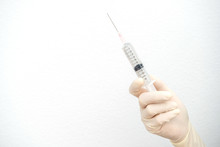 Close Up Of Nurse/Doctor Hand Holding A Plastic Syringe, Medical Injection In Hand. A Syringe Is A Small Tube With A Thin Hollow Needle At The End. Syringes Are Used For Putting Liquids Into Things.