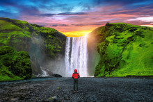 Skogafoss Waterfall In Iceland. Guy In Red Jacket Looks At Skogafoss Waterfall.