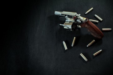 Revolver gun and Bullet 38 mm size on black fabric background.