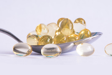 Vitamin D supplement pills close up or macro view in a spoon suggesting choosing a natural alternative to lower the risk of illness, cholesterol and liver disease