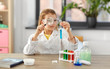 © Syda Productions - education, science and children concept - girl in goggles with magnifier studying test tube with chemical at home laboratory