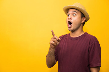 Young asian man looking at copy blank space on yellow background.