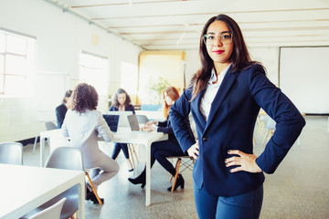 Wall Mural - Confident Asian businesswoman holding hands in hips. Beautiful young woman in eyeglasses looking at camera. Business concept