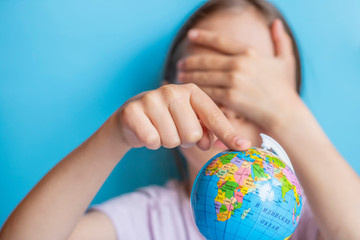 A child twists the globe with his finger, dreaming of traveling around the world
