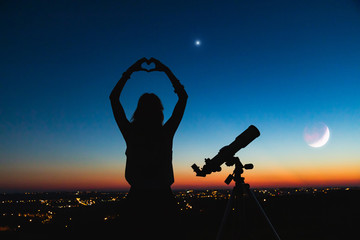 Wall Mural - silhouette of a woman and telescope with twilight sky.