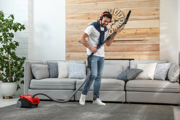 Canvas Print - Young man having fun while vacuuming at home