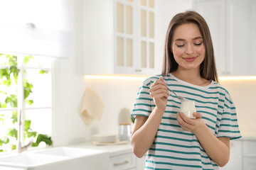 Canvas Print - Young attractive woman with tasty yogurt in kitchen. Space for text