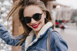 © Look! - Caucasian girl with glad face expression walking around city in spring morning and laughing. Outdoor shot of magnificent white lady in dark sunglasses wears denim attire.