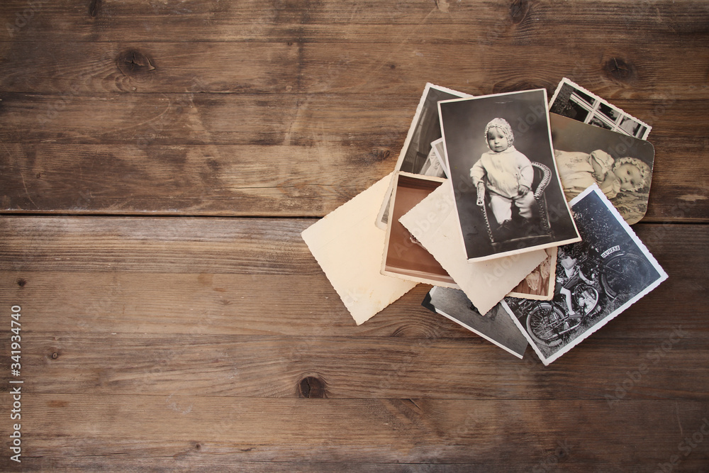 old vintage monochrome photographs in sepia color are scattered on a wooden table, the concept of genealogy, the memory of ancestors, family ties, memories of childhood - obrazy, fototapety, plakaty 