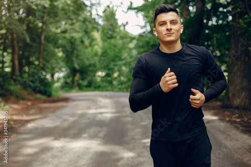Fotografía Handsome man in a park. Sportsman in a sportswear. Guy training