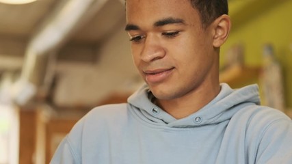 Wall Mural - Handsome concentrated young african guy student studying doing homework.