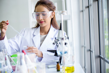 attractive young asian scientist woman lab technician assistant analyzing sample in test tube at lab