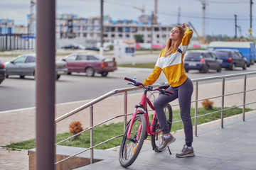 Wall Mural - Young, athletic girl in the city with a bike in the parking lot near a shopping center.