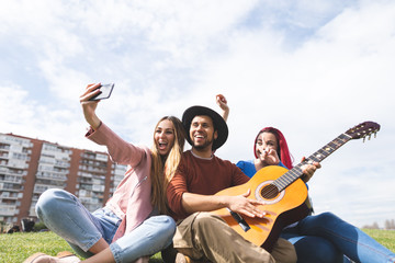 Group of Friends Playing Guitar Outdoors and Taking Selfie.