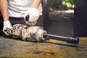 Wall Mural - Professional mechanic man holding a big air impact wrench tools on the table, repair maintenance heavy machinery