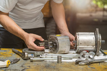 Professional Mechanic Man Inspection Hydraulic Gear Pump Of Wheel Loader In Workshop, Repair Maintenance Heavy Machinery