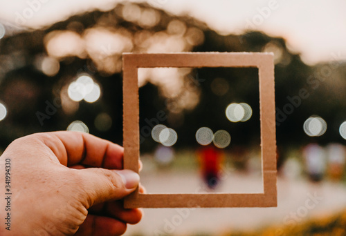 Cuadros en Lienzo Hand holding blank paper frame with nature bokeh background
