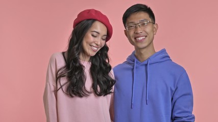 Poster - Young smiling loving couple isolated over pink wall background blowing kisses.