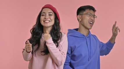 Poster - Young positive cheery loving couple isolated over pink wall background dancing.