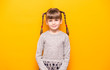 © Svetlana - Portrait of smiling little girl in grey dress over yellow background.