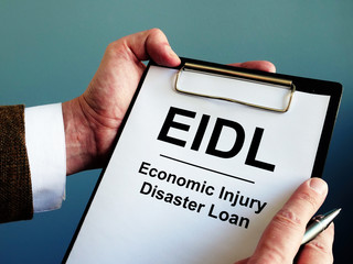 Wall Mural - Businessman reads about EIDL The Economic Injury Disaster Loan Program.