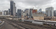Wide angle view of partial Chicago skyline behind an active train yard on overcast day