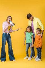 Wall Mural - angry mother yelling into megaphone on husband and sad children on yellow