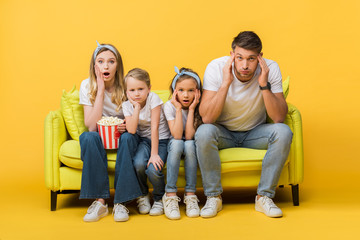 Wall Mural - shocked parents and kids watching movie on sofa with popcorn bucket on yellow