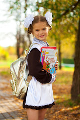 Wall Mural - Happy little schoolgirl in autumn park