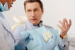 © LIGHTFIELD STUDIOS - selective focus of african american dentist in latex gloves holding teeth model and dental instrument near man