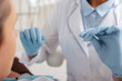 © LIGHTFIELD STUDIOS - selective focus of dentist in latex gloves holding dental floss near patient