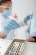 © LIGHTFIELD STUDIOS - selective focus of african american dentist in medical mask and face shield taking stainless dental mirror