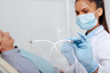 © LIGHTFIELD STUDIOS - selective focus of african american dentist in medical mask holding face shield near patient