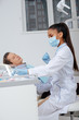 © LIGHTFIELD STUDIOS - african american dentist in medical mask touching face shield near patient