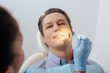 © LIGHTFIELD STUDIOS - selective focus of african american dentist in latex glove holding dental mirror near handsome patient