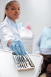 © LIGHTFIELD STUDIOS - selective focus of african american dentist in latex glove taking dental instrument