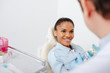 © LIGHTFIELD STUDIOS - selective focus of cheerful african american woman in braces near dentist holding teeth model