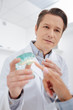© LIGHTFIELD STUDIOS - selective focus of dentist looking at patient pointing with finger at teeth model