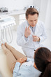 © LIGHTFIELD STUDIOS - overhead view of dentist pointing with finger at mouth and looking at african american patient