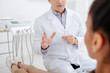 © LIGHTFIELD STUDIOS - cropped view of dentist gesturing near african american patient