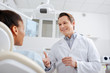 © LIGHTFIELD STUDIOS - selective focus of happy dentist looking at african american patient and gesturing in clinic