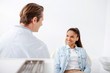 © LIGHTFIELD STUDIOS - selective focus of happy african american woman in braces looking at orthodontist in clinic