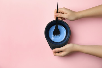 Woman preparing dye for hair coloring on pink background, top view. Space for text