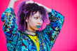 © beavera - Portrait of african american woman brushing her afro hair with hand outdoors. Teen millennial woman with curly hair and fashion clothing isolated on pink background. Bright psychedelic colors concept.