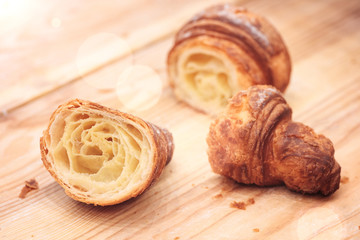 Poster - Croissant sliced on wooden table in restaurant with sun rays